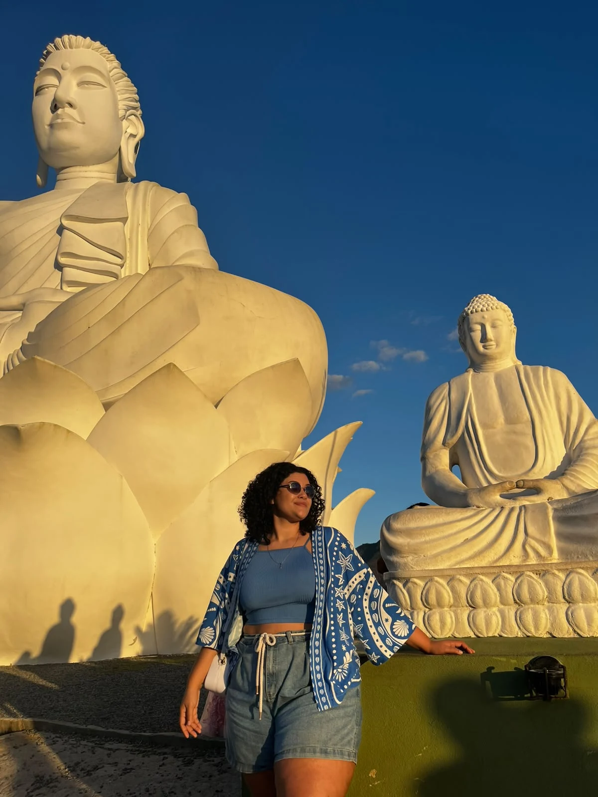 Criadora do guia em um passeio entre grandes esculturas de Buda
